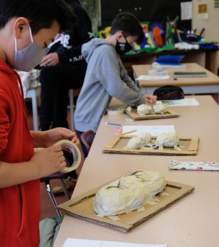 This is a collection of photos of students designing and making their relief sculptures out of newspaper and paper mache